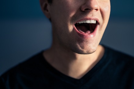 大きく口を開けて発声する男性